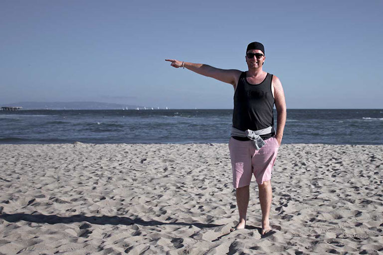 Félix Ossa - Dónde está Colombia? - Imagen de un hombre en la playa apuntando su mano hacia la izquierda